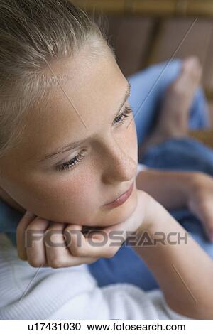 Stock Image - Portrait of Caucasian pre-teen girl with chin in hand looking down.. Fotosearch