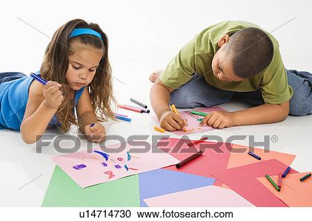 Stock Image - Young latino boy and girl coloring on construction paper and smiling.. Fotosearch