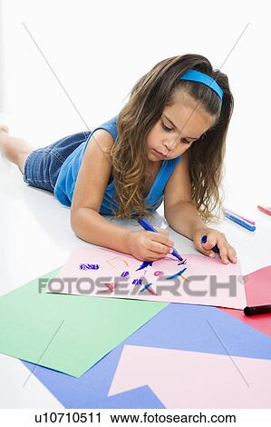 Stock Image - Young latino girl coloring on construction paper.. Fotosearch