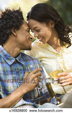 Stock Image - Affectionate couple drinking wine outdoors. Fotosearch
