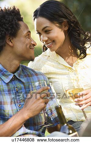 Stock Photo - Couple having wine on romantic park picnic. Fotosearch