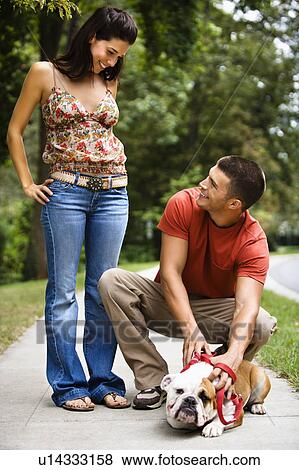 Stock Photo - Couple on the sidewalk with their dog. Fotosearch