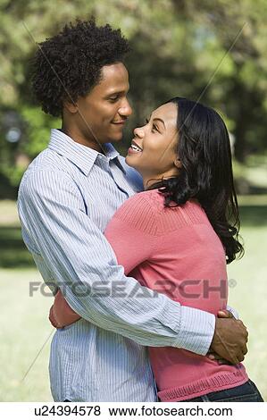 Stock Photo - Couple smiling and embracing in park. Fotosearch