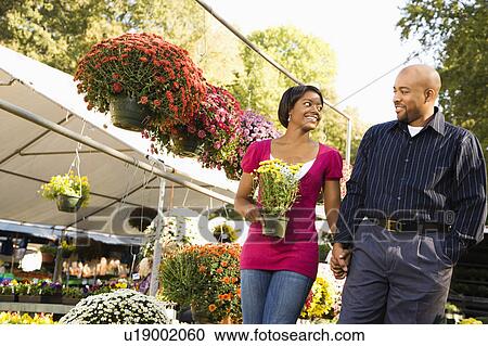 Stock Image - Happy smiling couple picking out flowers. Fotosearch