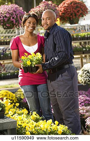 Stock Photo - Happy smiling couple picking out flowers at outdoor plant market.. Fotosearch