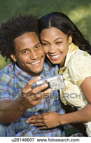 Happy smiling couple taking pictures together in park with digital camera. View Large Photo Image Stock Photo - Happy smiling couple taking pictures together in park with digital camera.. Fotosearch