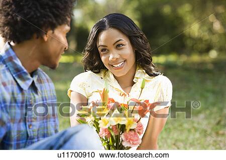 Stock Image - Man giving smiling woman bouquet of flowers.. Fotosearch