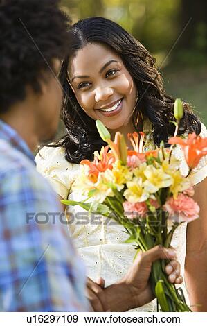 Stock Photo - Man giving smiling woman bouquet of flowers. Fotosearch