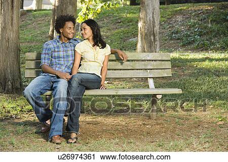 Smiling couple sitting on park bench View Large Photo Image Stock Image - Smiling couple sitting on park bench . Fotosearch