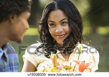 Woman holding flower bouquet smiling at man View Large Photo Image Stock Photography - Woman holding flower bouquet smiling at man. Fotosearch