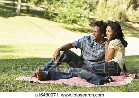 Stock Image - Young couple on a blanket in a park. Fotosearch