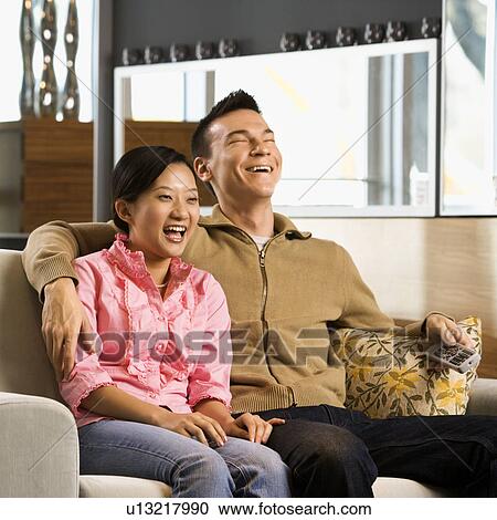 Couple laughing while watching television View Large Photo Image Stock Image - Couple laughing while watching television. Fotosearch