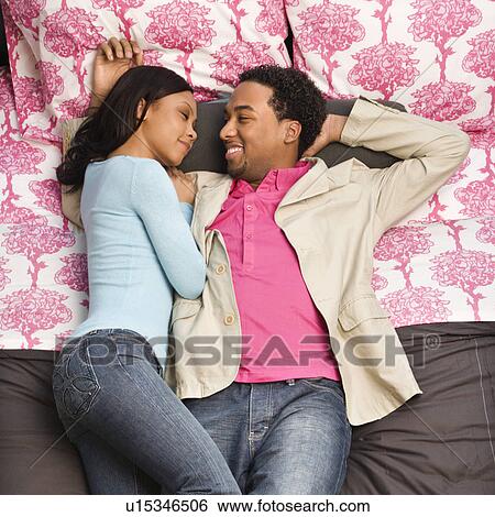 Couple laying on bed looking at each other View Large Photo Image Stock Photograph - Couple laying on bed looking at each other. Fotosearch