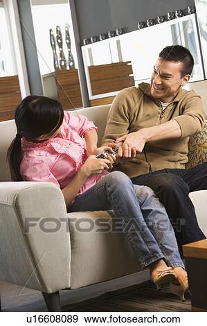 Couple on sofa fighting over TV remote View Large Photo Image Stock Photo - Couple on sofa fighting over TV remote. Fotosearch