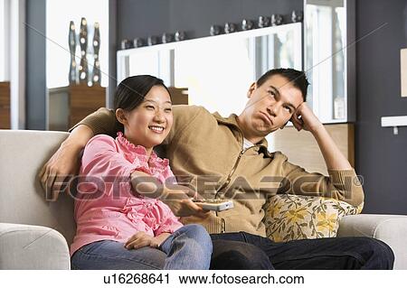 Couple sitting on couch watching TV View Large Photo Image Stock Image - Couple sitting on couch watching TV. Fotosearch