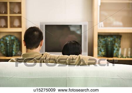 Couple sitting on couch watching TV View Large Photo Image Stock Photo - Couple sitting on couch watching TV. Fotosearch