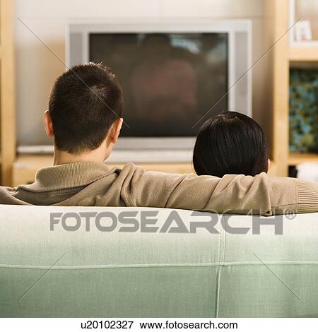Couple sitting on couch watching TV View Large Photo Image Stock Photo - Couple sitting on couch watching TV. Fotosearch
