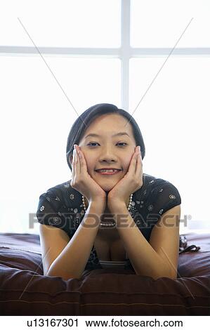 Stock Image - Female lying on bed . Fotosearch
