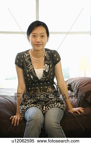 Stock Photography - Female sitting on bed.. Fotosearch
