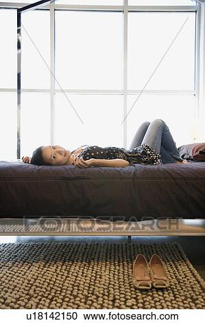 Stock Image - Woman lying on bed. Fotosearch