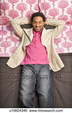 Young man laying on bed looking at viewer. View Large Photo Image Stock Photograph - Young man laying on bed looking at viewer.. Fotosearch
