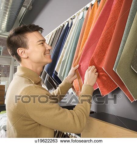 Young man looking at fabric swatches in retail store. View Large Photo Image Stock Image - Young man looking at fabric swatches in retail store.. Fotosearch
