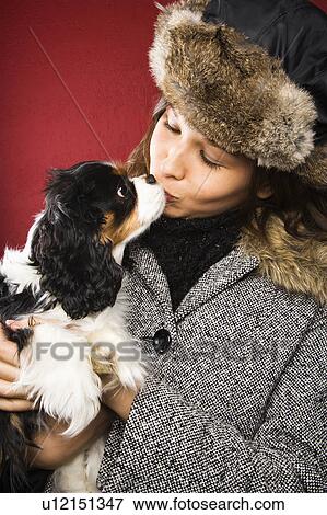 Stock Photo - Adult woman in winter outerwear kissing a dog.. Fotosearch