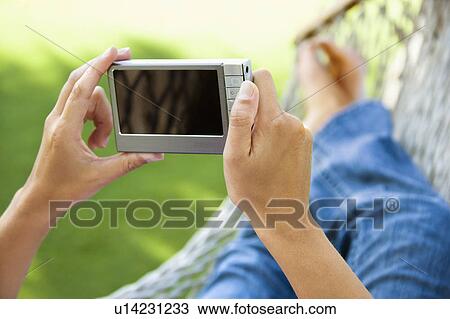 Stock Image - Hands holding while lying in hammock. Fotosearch