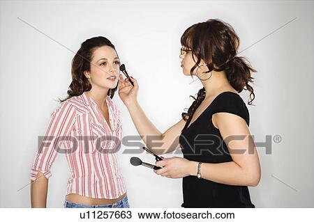 Stock Image - Makeup artist putting makeup on woman. Fotosearch