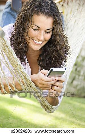Pretty young adult brunette female laying in hammock using PDA and smiling View Large Photo Image Stock Photography - Pretty young adult brunette female laying in hammock using PDA and smiling. Fotosearch