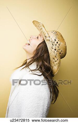 Stock Photography - Profile of young adult woman wearing cowboy hat leaning backwards laughing. Fotosearch