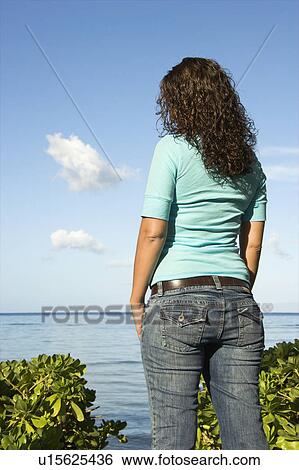Rear view of woman looking out over body of water View Large Photo Image Stock Photograph - Rear view of woman looking out over body of water. Fotosearch