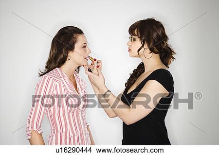 Picture - Side view of makeup artist putting lipstick on young woman. Fotosearch