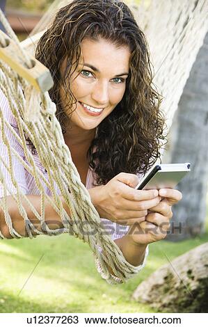 Stock Image - Woman in a hammock with a cellphone. Fotosearch