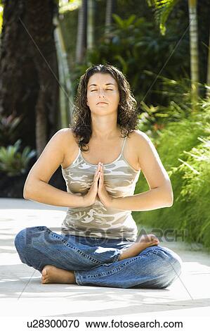 Stock Image - Woman meditating on the sidewalk. Fotosearch