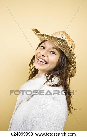 Stock Image - Young adult woman wearing cowboy hat smiling at viewer.. Fotosearch