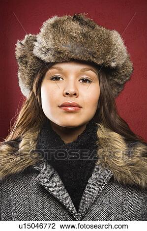 Stock Image - Young adult woman wearing fur hat looking at viewer.. Fotosearch