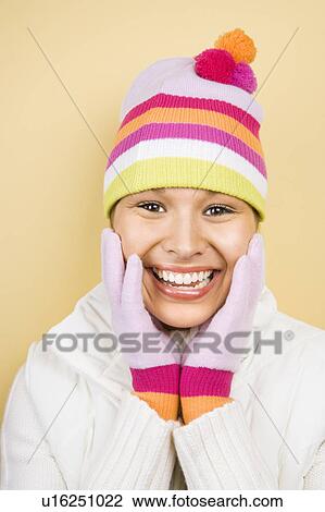 Young adult woman wearing winter hat and gloves with hands to face smiling at viewer View Large Photo Image Stock Image - Young adult woman wearing winter hat and gloves with hands to face smiling at viewer. Fotosearch