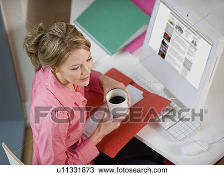 Female drinking coffee at her desk View Large Photo Image Stock Image - Female drinking coffee at her desk. Fotosearch