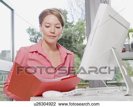 Female looking in a folder at her desk View Large Photo Image Stock Image - Female looking in a folder at her desk. Fotosearch