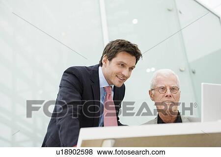 Two men looking at a display View Large Photo Image Stock Photo - Two men looking at a display. Fotosearch