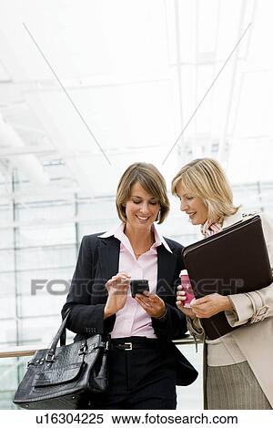 Two women looking at device View Large Photo Image Stock Photography - Two women looking at device. Fotosearch