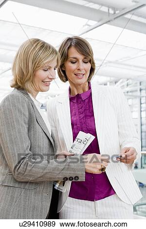 Two women looking at ticket View Large Photo Image Stock Photo - Two women looking at ticket. Fotosearch