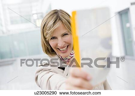 Stock Image - Woman holding ticket smiling. Fotosearch