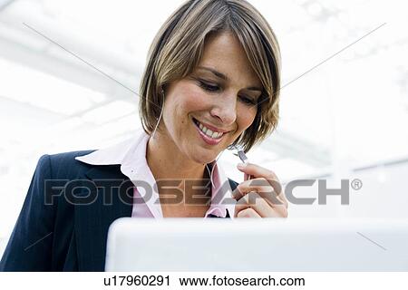 Stock Image - Woman smiling working at computer. Fotosearch