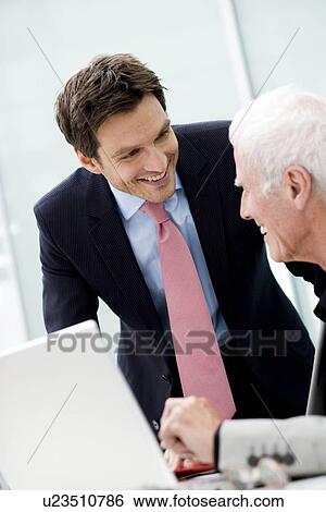 Stock Photograph - Younger man talking to older man. Fotosearch
