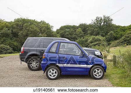 Stock Image - Electric car next to four wheel drive. Fotosearch