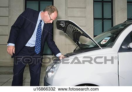 Man looking at engine of electric car View Large Photo Image Stock Image - Man looking at engine of electric car. Fotosearch