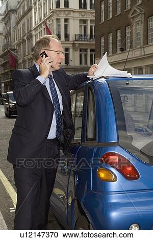 Stock Image - Man on phone and looking at papers. Fotosearch