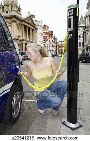 Young woman charging electric car View Large Photo Image Stock Photography - Young woman charging electric car. Fotosearch